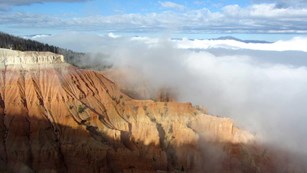 Thick clouds around orange cliffs.