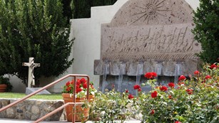 A grave site and fountain in a landscaped garden