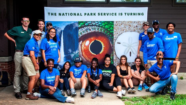 SCA youth volunteers pose in front of a centennial banner