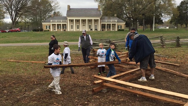 Young people repairing a rail fence