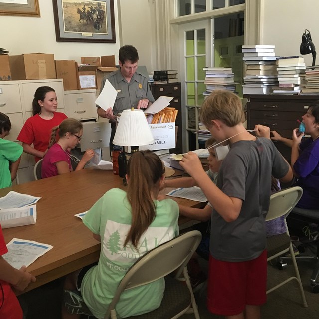 Students work with a park ranger in a library setting