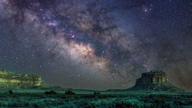 Fajada Butte shown under a galactic sky with visible stars and a green hue.