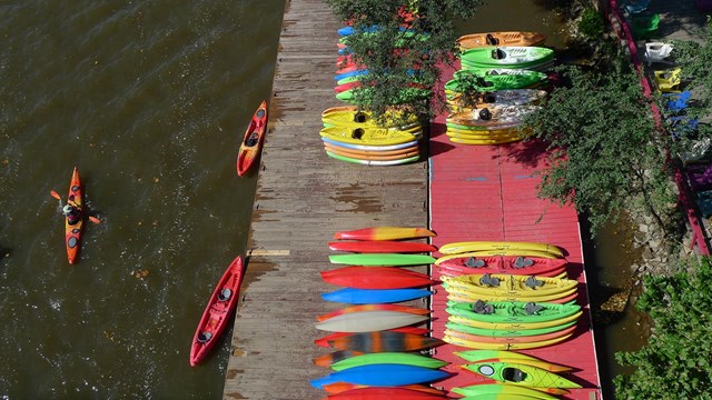 Several colorful kayaks stacked on a floating dock along the water.