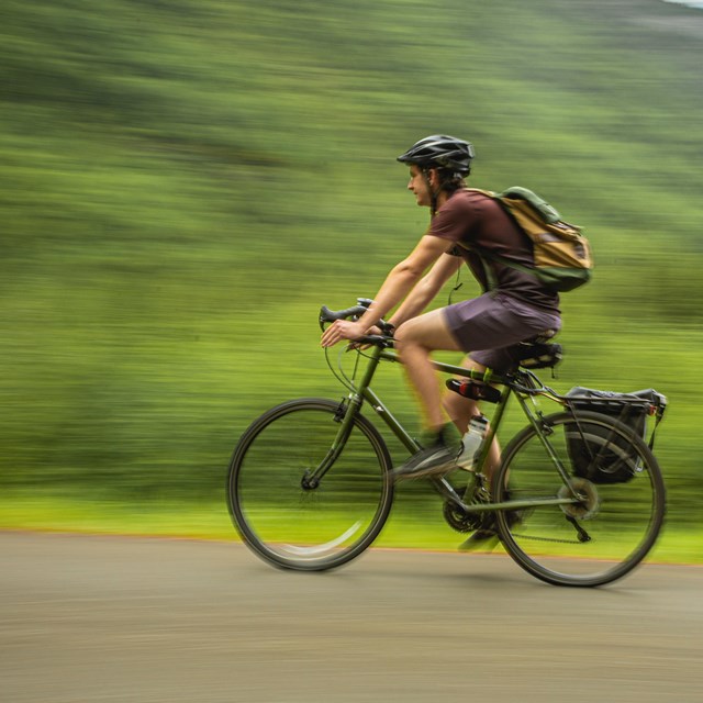 a man wearing a helmet bicycles on a path
