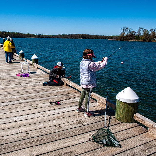 Several people fish from a pier.