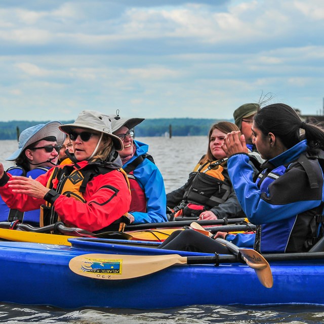 A group of kayakers gather to talk while on the water.