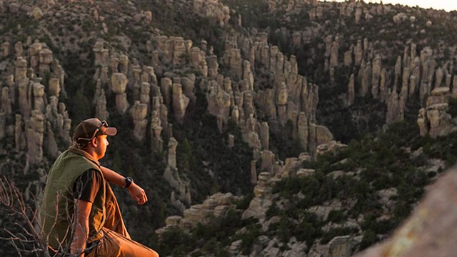 A hiker watches the sunset from a scenic overlook