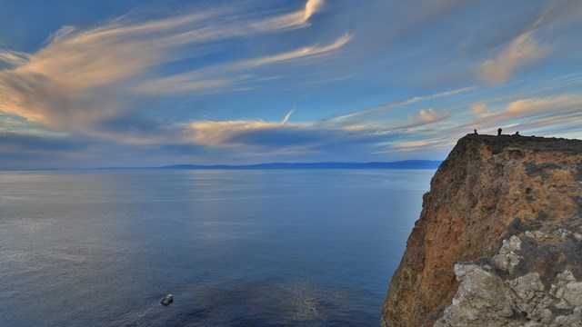 HIkers on coastal bluff overlooking ocean at sunset. ©Tim Hauf, timhaufphotography.com