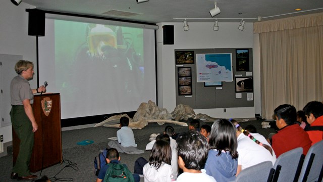 Kids watching diver on screen. 