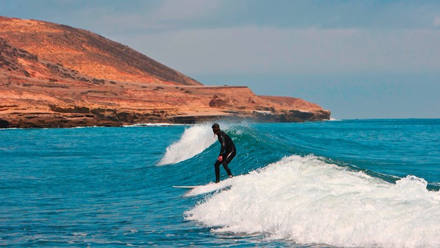 Surfer on wave with island in background. ©Tim Hauf, timhaufphotography.com