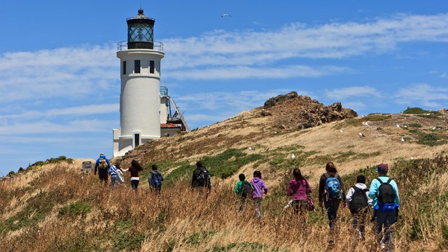 Visitors hiking near a lighthouse.