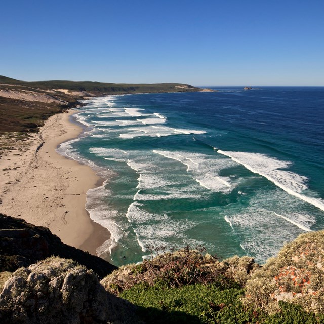 Rocky headland leading to white sand coastline.