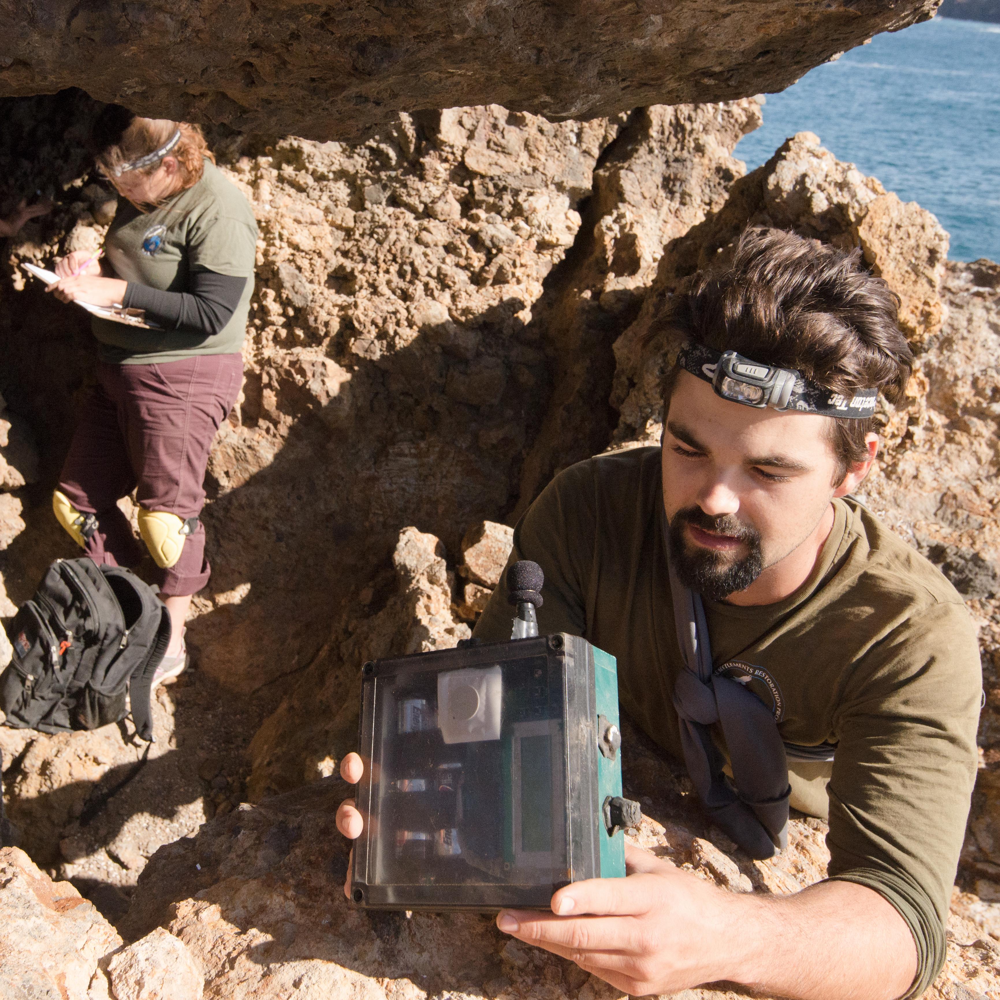 Two scientist in cave along coast.
