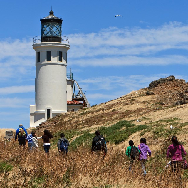 visitors hiking next to lighthouse