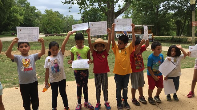 Eight Junior Rangers lined up holding up paper certificates.