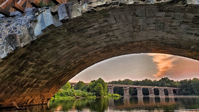 Aqueduct over a river at sunset.