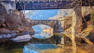 A view through an aqueduct arch to a bridge in the distance.
