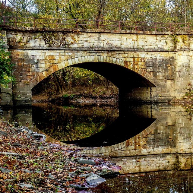 An single arch aqueduct spans a creek.