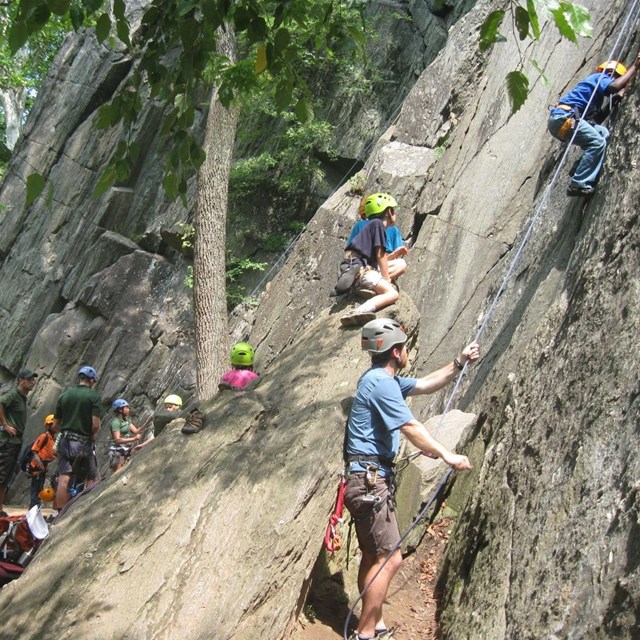 Youth with instructors rock climbing at the park.