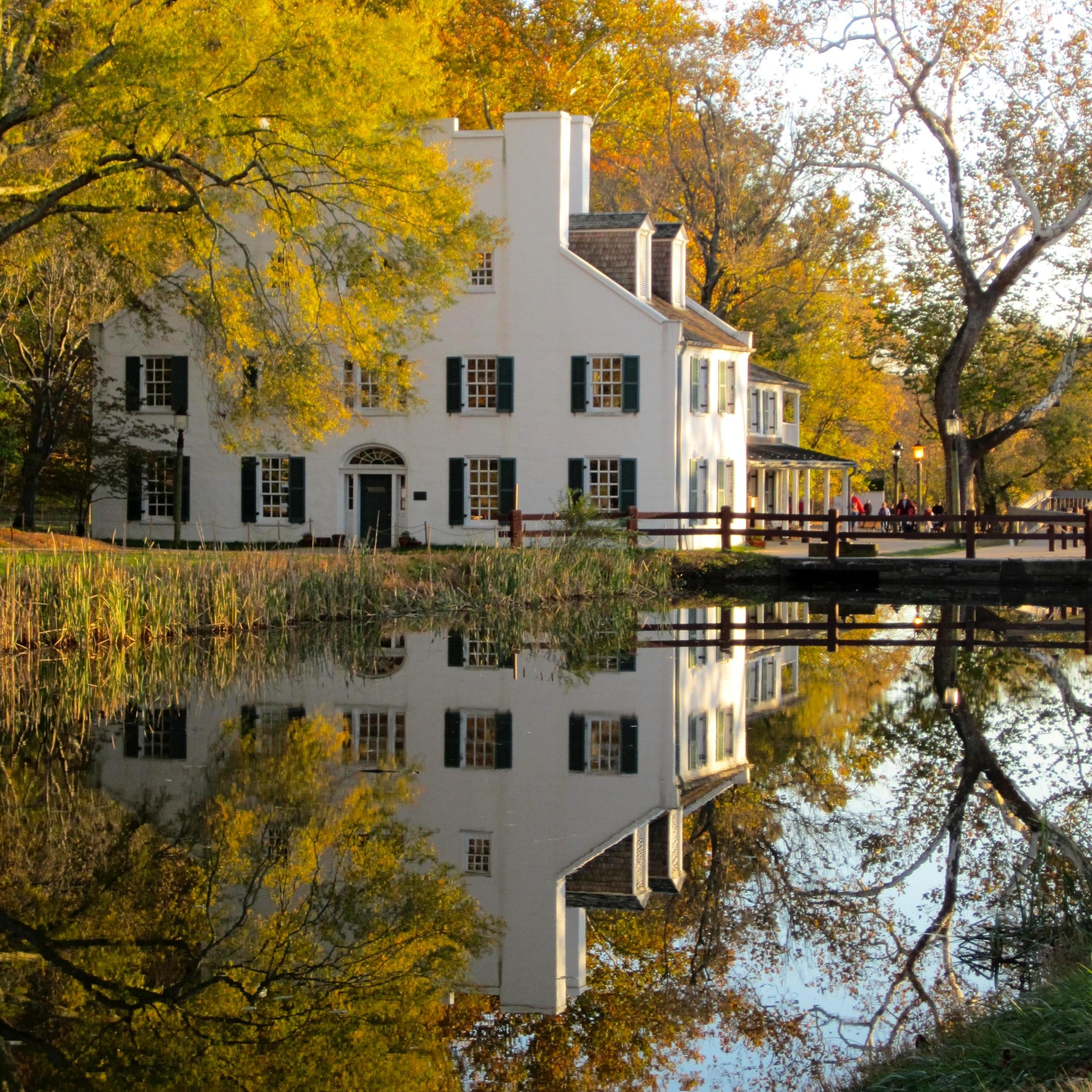 Great Falls Tavern Visitor Center in autumn reflecting in the watered canal. 