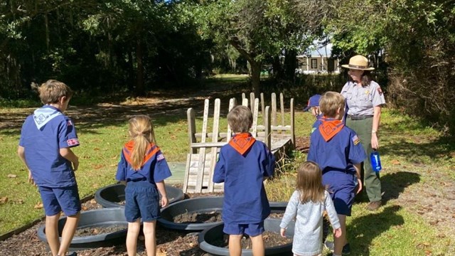 A scout troop listens to a Ranger talk about historic resources