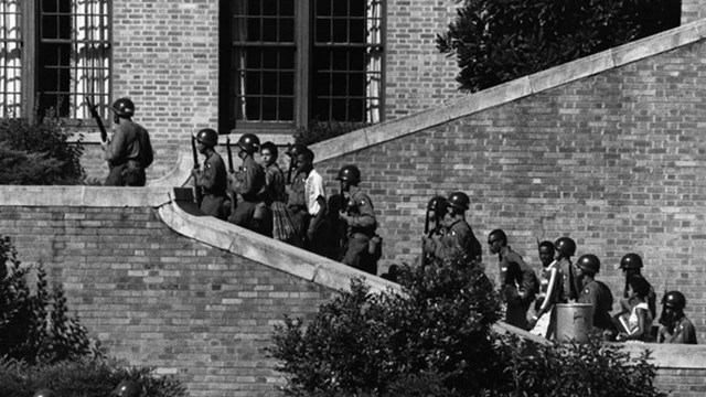 The Little Rock Nine are escorted up the stairs leading into Central High by the 101st Airborne.