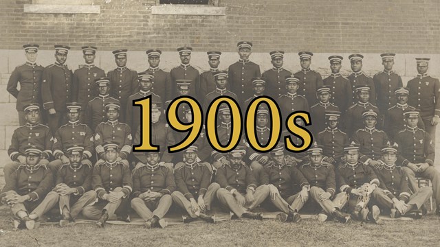 Buffalo Soldiers in formal uniforms sitting in 4 rows together. All looking stoic at viewer