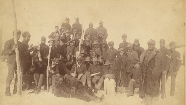 Sepia photo of a group of African Americans in military uniforms of the late 1800s