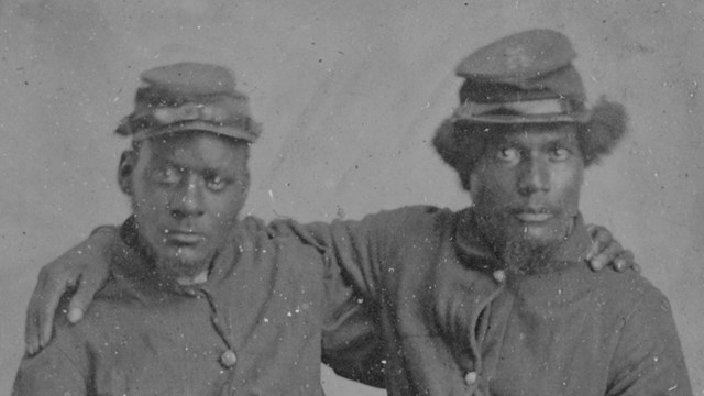 Black and white photo of African American brothers in Union army uniforms staring at the camera