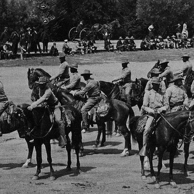 Black soldiers mounted atop horses in a field