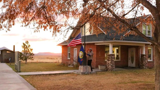 A ranger is taking down the American flag and the Idaho state flag at the end of the day.