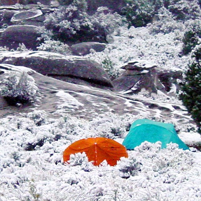 Two tents in the snow at a campsite in the City of Rocks.