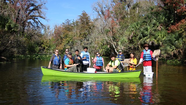 A group of volunteers in a canoe smiles.