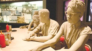 color photo of statues depicting sitting at a lunch counter