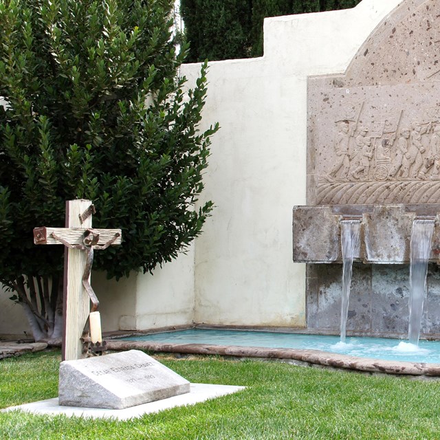 stone cross on left in front of fountain and small pool