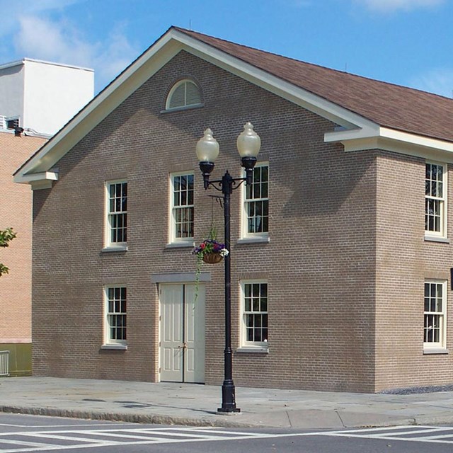 a brick building with lamppost and tree on right