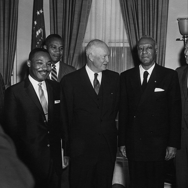 B&W photo of men standing in line posing for photo