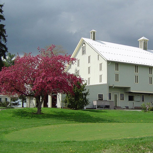 grey sky with large farm building and putting green