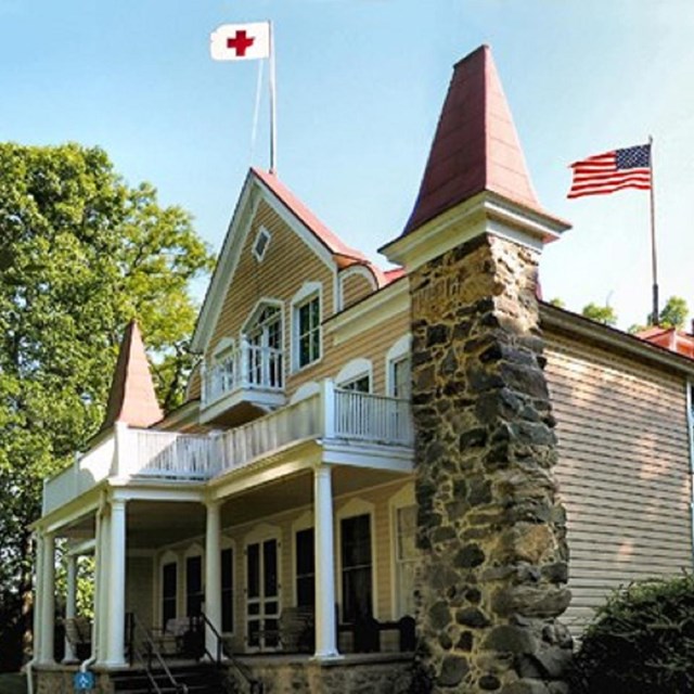 large 2 story house with red cross flag on flagpole on top