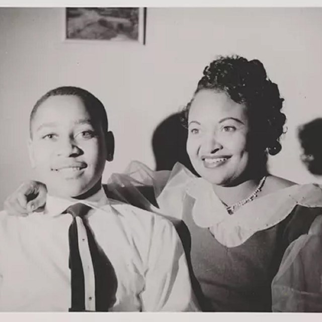 african american boy and adult woman. woman has arm around boy's shoulder. both are smiling.
