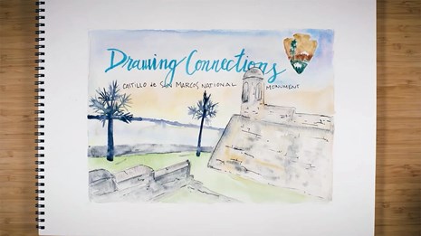 Watercolor painting of a seaside fort, resting on a table