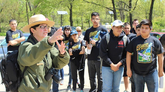 Park ranger points while talking as children listen