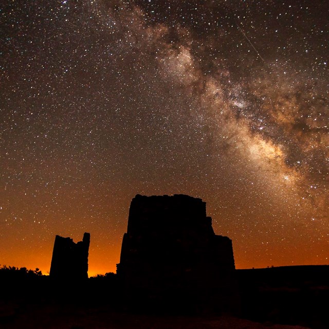 Night sky view of Milky Way with silhouettes of historic ruins in foreground