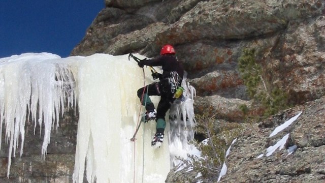 Male ice climber ascending a frozen waterfall