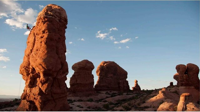 A male climber high above on a rock at Arches National Park