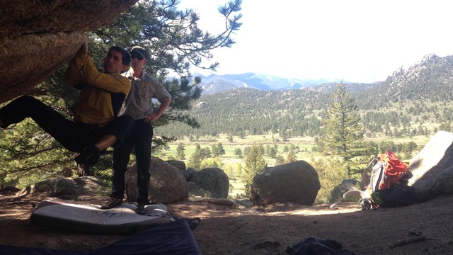 Man bouldering under ranger observation at Rocky Mountain National Park