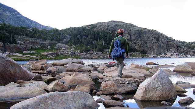 Man on approach to mountain in Rocky Mountain National Park carrying climbing gear