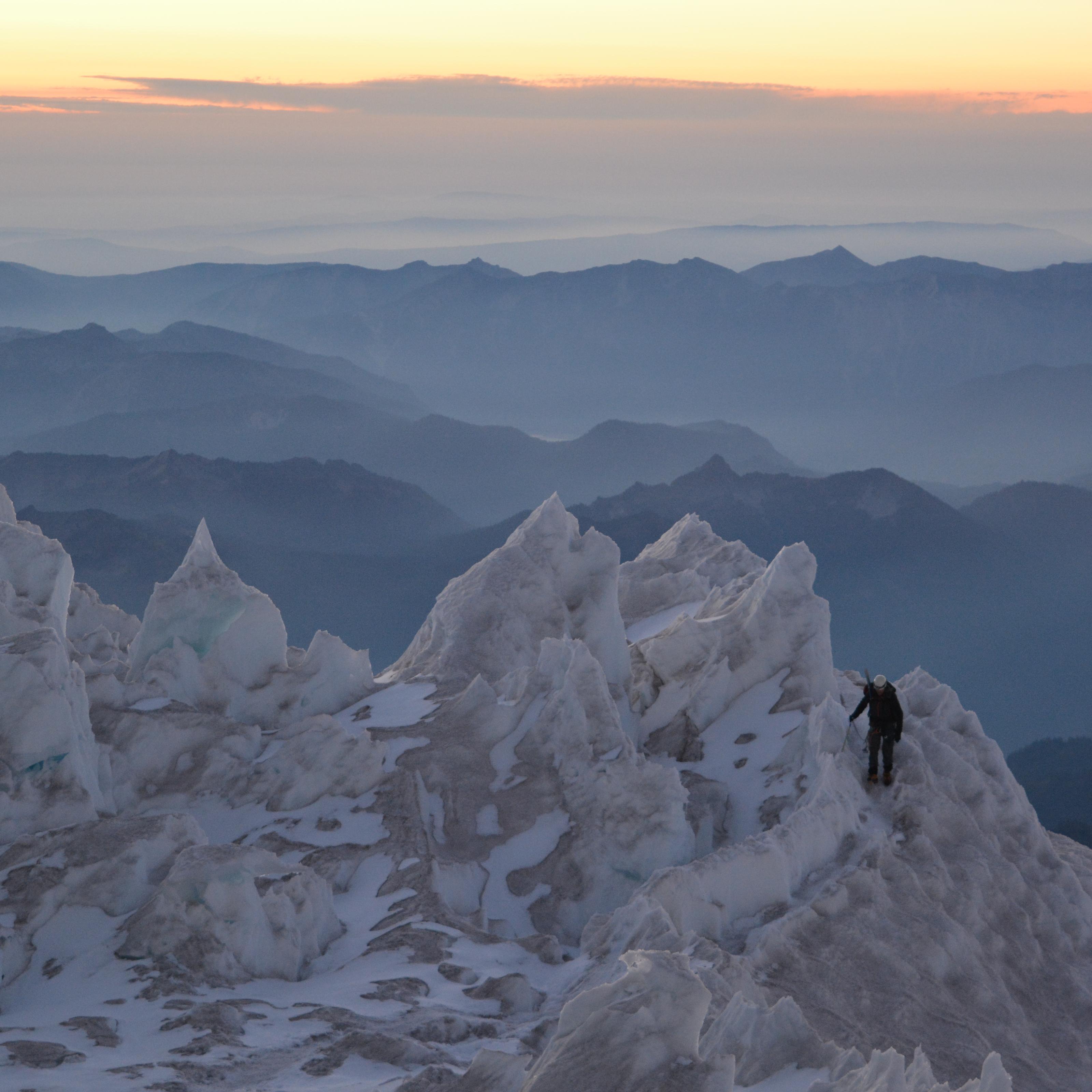 solo figure traversing through glacier seracs, the sun is setting