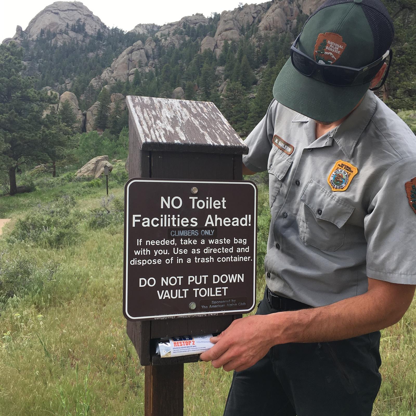 Climbing Ranger stocking a Wag Bag dispenser at a climbing access trail