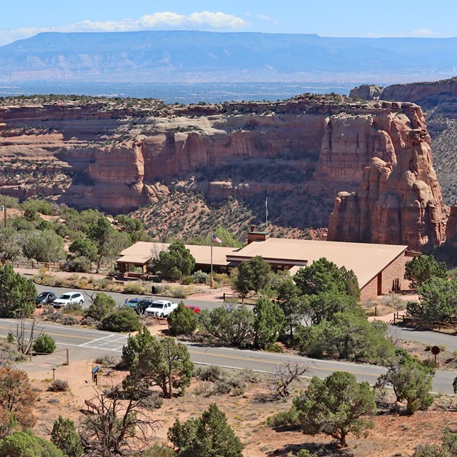 View looking down on visitor center, with canyons in background and in distance flat-topped mountain